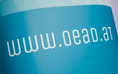 Blauer Plakat mit dem weißen Schriftzug "www.oead.at" 
