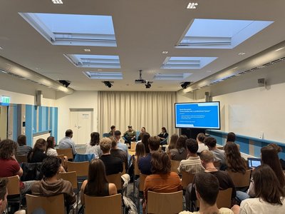 Panellists sitting in front of the room and audience listening