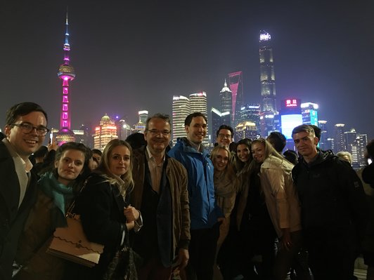 Evening in the city, illuminated skyscrapers in the background, group of people in front looking at the camera