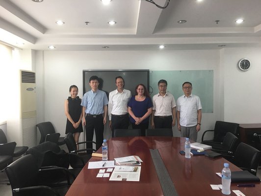 Vertreter der Uni Salzburg und Fudan Universität stehen mit Alexandra Wagner vom OeAD-Kooperationsbüro vor einem Sitzungstisch für ein gemeinsames Gruppenfoto.