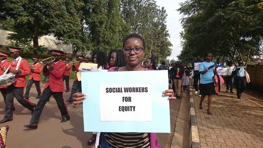 Demonstrationszug in der Stadt Kingali in Ruanda. Eine Frau hält ein Schild in die Höhe.