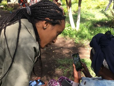 Two women with mobile phones in their hands are talking to each other