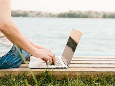 Sideview man using laptop by the water
