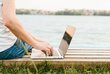 Sideview man using laptop by the water