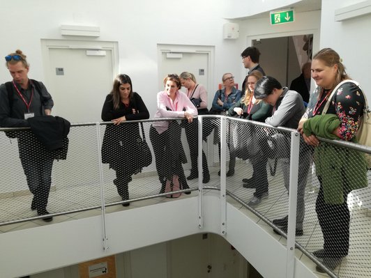 Visitors stand at a railing in the staircase of the guest house.