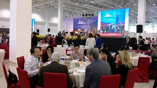 Evening reception at the APAIE trade fair in Taiwan with elegantly decorated tables and trade fair participants in evening wear.