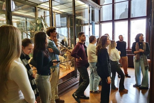 Eine Gruppe von Personen im naturhistorischen Museum, alle Blicke sind nach rechts auf etwas außerhalb des Bilds gerichtet