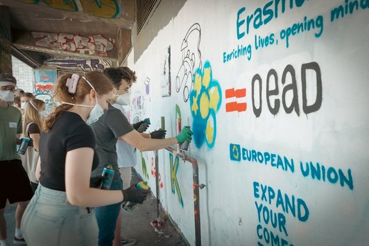 junge Menschen sprayen Graffiti auf eine Wand 