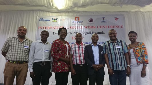 Group of people posing for a photo in front of a big conference poster