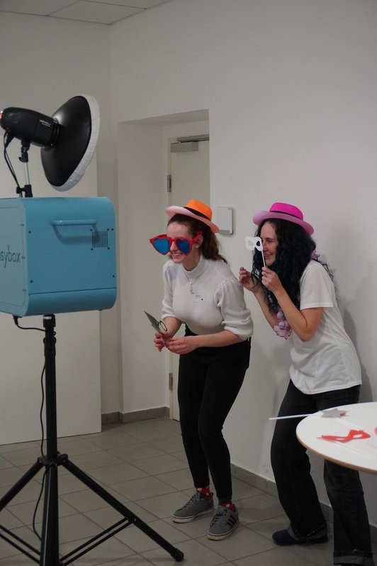 Two scholarship holders taking fun photos using a photo box