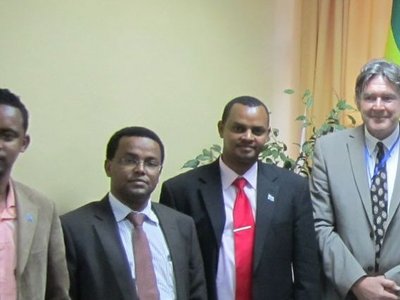 A group of eight formally dressed men standing around a table