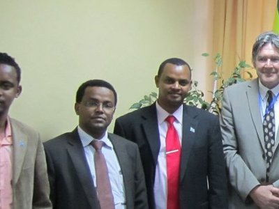 A group of eight formally dressed men standing around a table