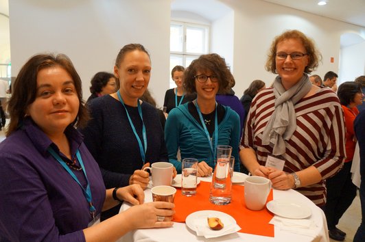 4 Frauen stehen um einen Tisch