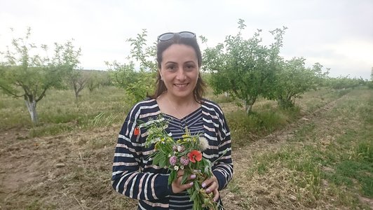 Smiling woman with a bunch of flowers in her hands is looking at the camera