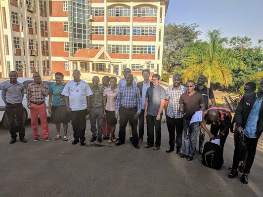 Group of people standing in a row and posing for a picture in front of a builiding