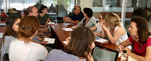 Group of people sitting together on a table talking to each other