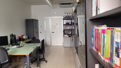 Ein Büro mit Schreibtisch auf einer Seite und einem Regal mit Lehrbüchern für Deutsch als Fremdsprache auf der anderen Seite