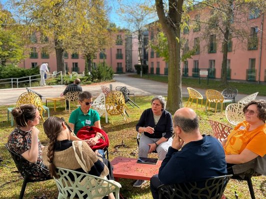 Foto von Personen im Sitzkreis, welche sich unterhalten