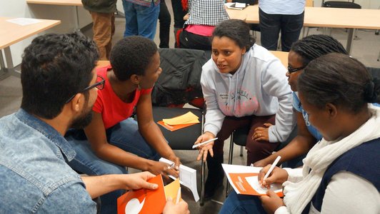 Five people sitting on chairs in a circle and discussing