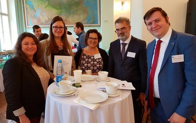 Gruppe von fünf Personen posiert an einem Stehtisch für ein Foto im Veranstaltungssaal