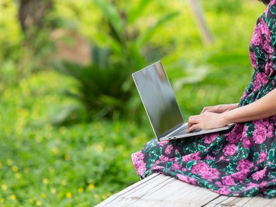 Girl wearing a floral dress sitting with her laptop