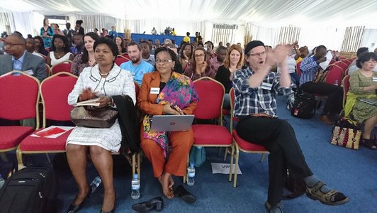 Many people sitting in a room with rows of chairs