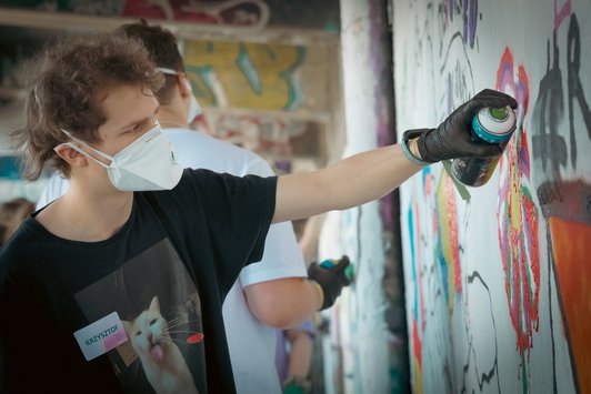 junge Menschen sprayen Graffiti auf eine Wand 