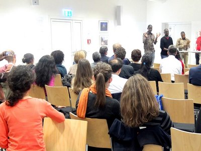 Five people are giving a speech in front of an audience.