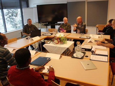 Group of people sitting around tables and one man is talking
