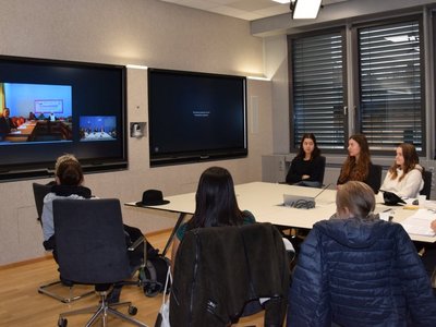 Project team in Austria in front of big screens in a room, connected to Palestinian team virtually