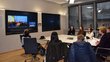 Project team in Austria in front of big screens in a room, connected to Palestinian team virtually