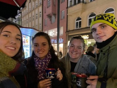 Four young students take a picture of themselves outside late in the evening. Everyone is dressed vor colder weather.