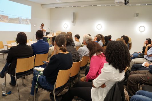 Group of people looking at the presentation of a man who talks about the project