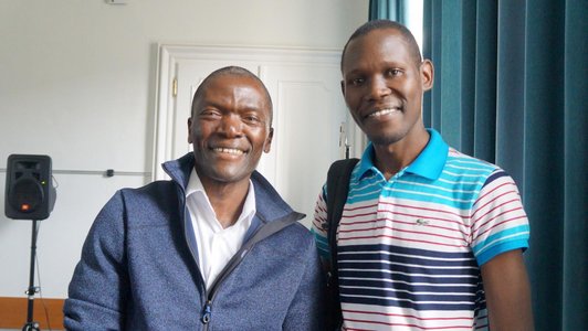Paul Yillia from the IIASA standing next to one student from East Africa, both are smiling into the camera
