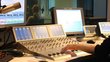 Radio studio with a person's hand operating a mixer.