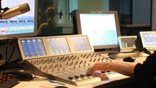 Radiostudio mit Hand einer Person, die ein Mischpult bedient.