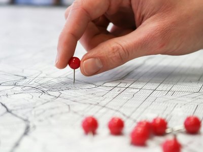 Hand, die eine Pinnadel auf eine Karte setzt