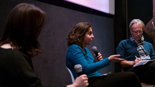 female panellist is talking into the microphone while addressing her comments to the audience in the cinema hall