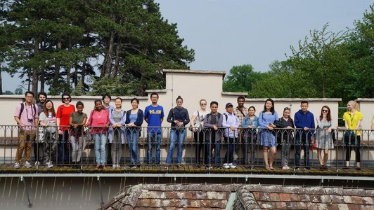 Many students from all over the world standing next to each other in the Laxenburg part area and smiling to the camera