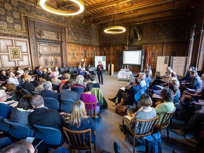 Vertreterinnen und Vertreter von Hochschulen sitzen in einem Oval und blicken zur Moderatorin