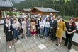 Zahlreiche Frauen und Männer stehen auf einer Terrasse in Alpbach und schauen in Richtung des Fotografen