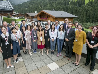  Numerous women and men stand on a terrace in Alpbach and look in the direction of the photographer