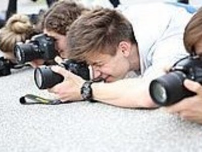 Four photographers lying on the ground to take a photo. Everyone looks through their camera.