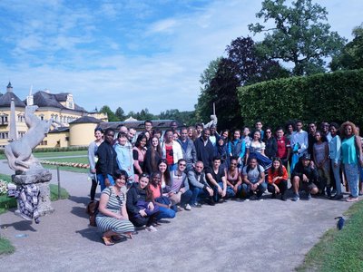 Die Stipendiaten bei einem Gruppenfoto vor einem Schloss mit Park und Einhornstatuen in Salzburg.