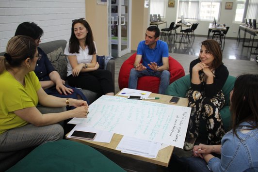 Group of people sitting on couches and beanbags around a table and talk to each other