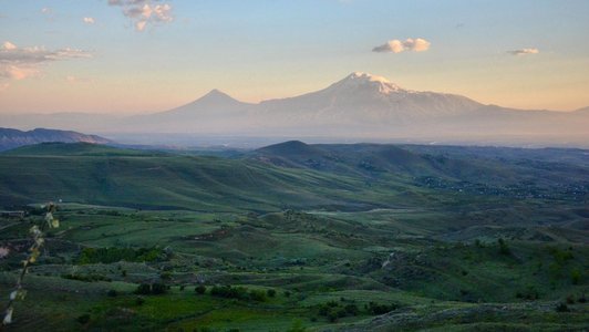 Green hilly landscape and high and snow covered mountains in the background