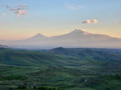 Green hilly landscape and high and snow covered mountains in the background