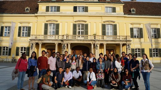 Many scholarship holders from all around the world standing in front of the yellowish old building at Laxenburg and posing for the photo