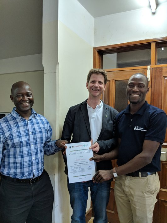 Three man posing for a picture holding a slip of paper in their hands