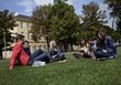 Studenten und Studentinnen sitzen mit ihren Büchern in einer Wiese und lernen.